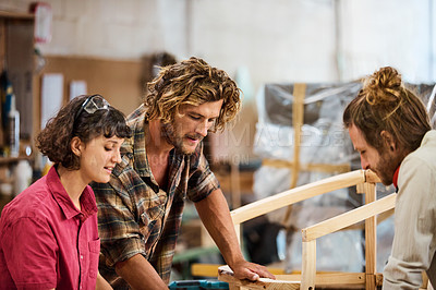 Buy stock photo Shot of three people working with wood in a furniture manufacturing workshop