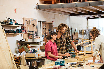 Buy stock photo Shot of three people working with wood in a furniture manufacturing workshop