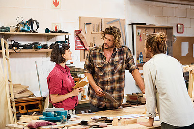Buy stock photo Shot of three people working with wood in a furniture manufacturing workshop