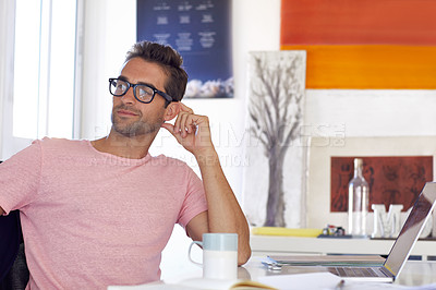 Buy stock photo Shot of a handsome young businessman sitting at his desk