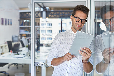 Buy stock photo Cropped shot of a handsome businessman using his digital tablet at work