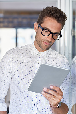 Buy stock photo Cropped shot of a handsome businessman using his digital tablet at work