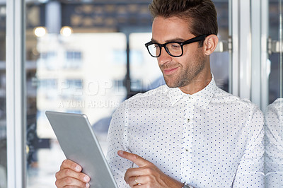 Buy stock photo Cropped shot of a handsome businessman using his digital tablet at work