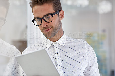 Buy stock photo Cropped shot of a handsome businessman using his digital tablet at work