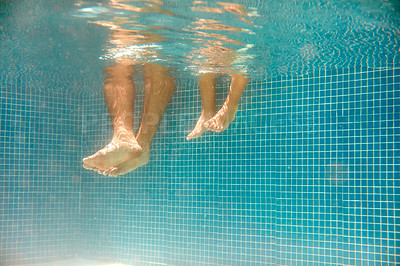 Buy stock photo Underwater shot of an unrecognizable father and son's bare feet in a swimming pool