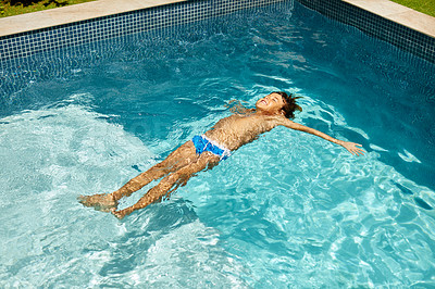 Buy stock photo Shot of a little boy floating in a swimming pool