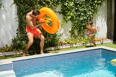 Buy stock photo Shot of a father and his son playing with water guns at the swimming pool