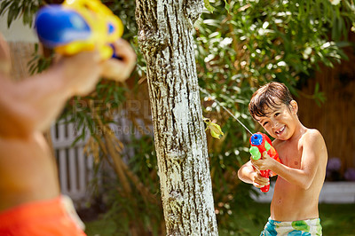 Buy stock photo Shot of a father and his son playing with water guns at the swimming pool