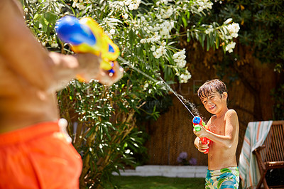 Buy stock photo Shot of a father and his son playing with water guns at the swimming pool