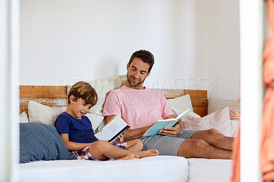 Buy stock photo Shot of a father and son reading and relaxing on the sofa at home