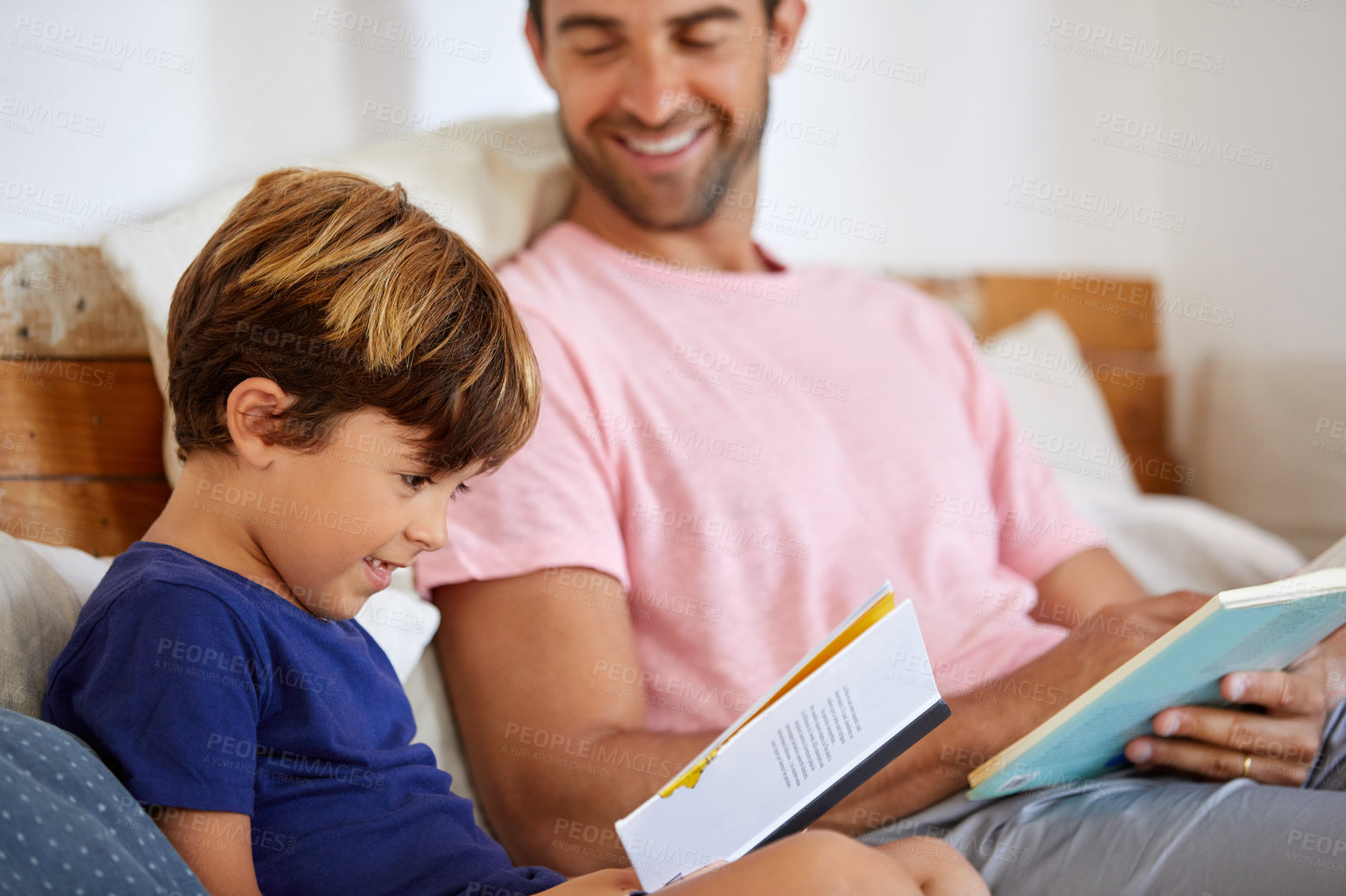 Buy stock photo Shot of a father and son reading and relaxing on the sofa at home