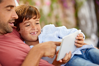 Buy stock photo Shot of a father and son using a digital tablet while relaxing together outside