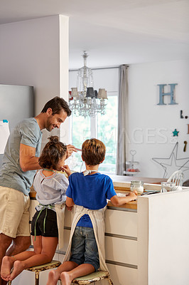Buy stock photo Rearview shot of a father helping his son and daughter bake in the kitchen at home