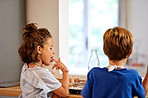 Rearview shot of a young brother and sister tasting batter in the kitchen at home