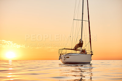 Buy stock photo Shot of a young couple going for an ocean cruise at sunset