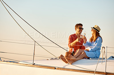 Buy stock photo Shot of a young couple drinking champagne together on an ocean cruise