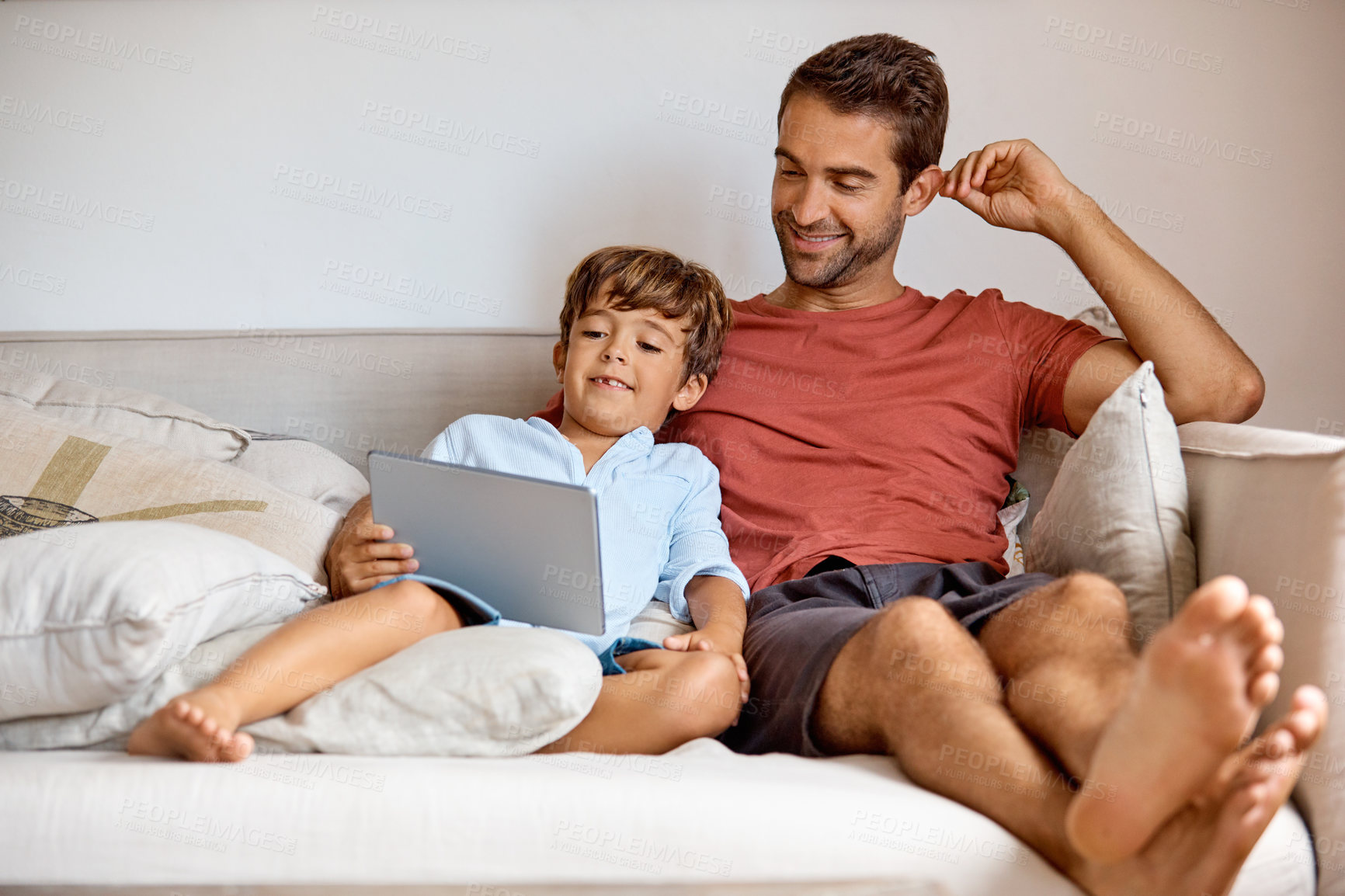 Buy stock photo Shot of a boy using a digital tablet while sitting with his father