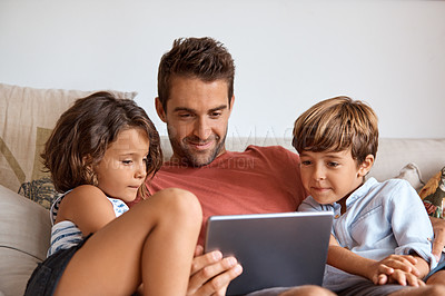 Buy stock photo Shot of a little girl and boy using a digital tablet while sitting with their father