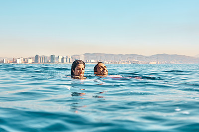 Buy stock photo Cropped shot of an affectionate young couple swimming in the ocean
