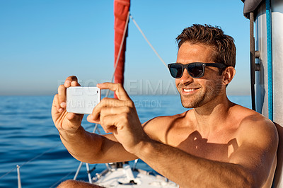 Buy stock photo Shot of a handsome young man using a mobile phone on a relaxing boat cruise
