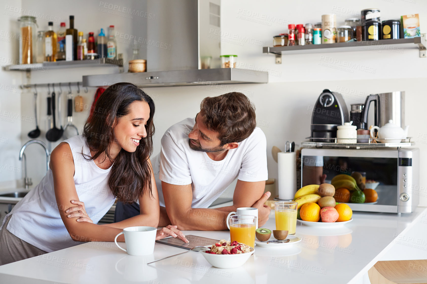 Buy stock photo Shot of a young couple using a digital tablet together during their morning routine at home