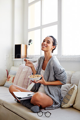 Buy stock photo Shot of a beautiful young woman going over some work while having breakfast in the morning at home