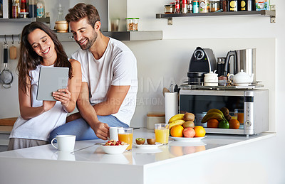 Buy stock photo Shot of a young couple using a digital tablet together during their morning routine at home