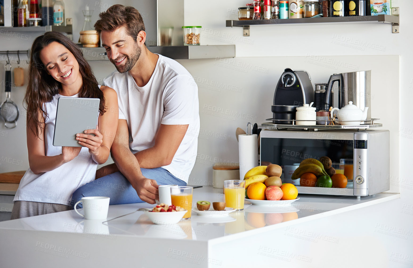 Buy stock photo Shot of a young couple using a digital tablet together during their morning routine at home