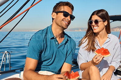 Buy stock photo Shot of a happy young couple eating watermelon on a relaxing ocean cruise