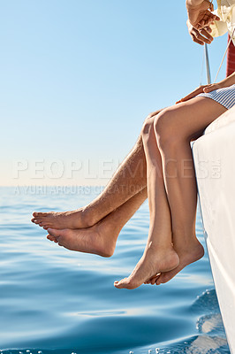Buy stock photo Cropped shot of a couple sitting with their feet off the side of boat on a cruise
