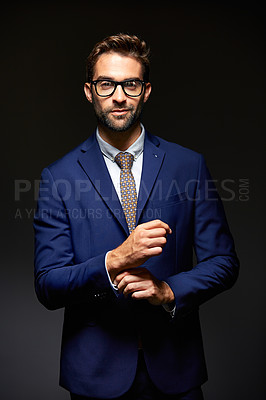 Buy stock photo Studio portrait of a handsome young businessman posing against a dark background