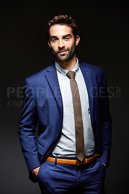 Buy stock photo Studio portrait of a handsome young businessman posing against a dark background