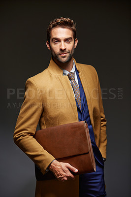 Buy stock photo Studio portrait of a handsome young businessman posing against a dark background