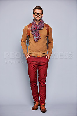 Buy stock photo Studio portrait of a handsome young man standing with his hands in his pockets against a grey background