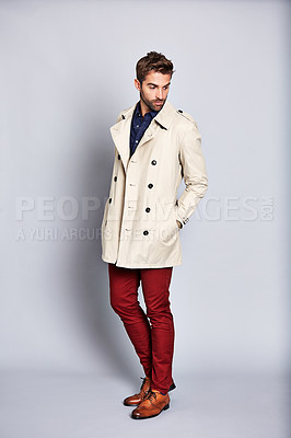 Buy stock photo Studio shot of a handsome young man posing in a trench coat against a grey background