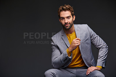 Buy stock photo Studio portrait of a handsome young businessman sitting against a grey background