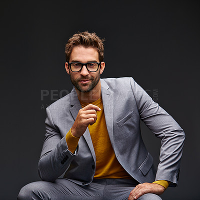 Buy stock photo Studio portrait of a handsome young businessman sitting against a grey background