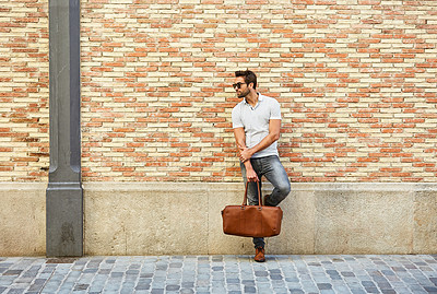 Buy stock photo Shot of a fashionable young man leaning against a brick wall outside