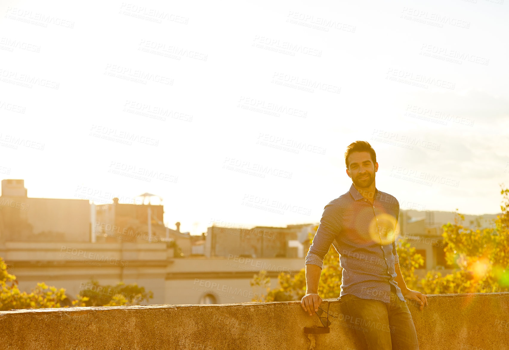 Buy stock photo Cropped shot of a man on a rooftop against a city background