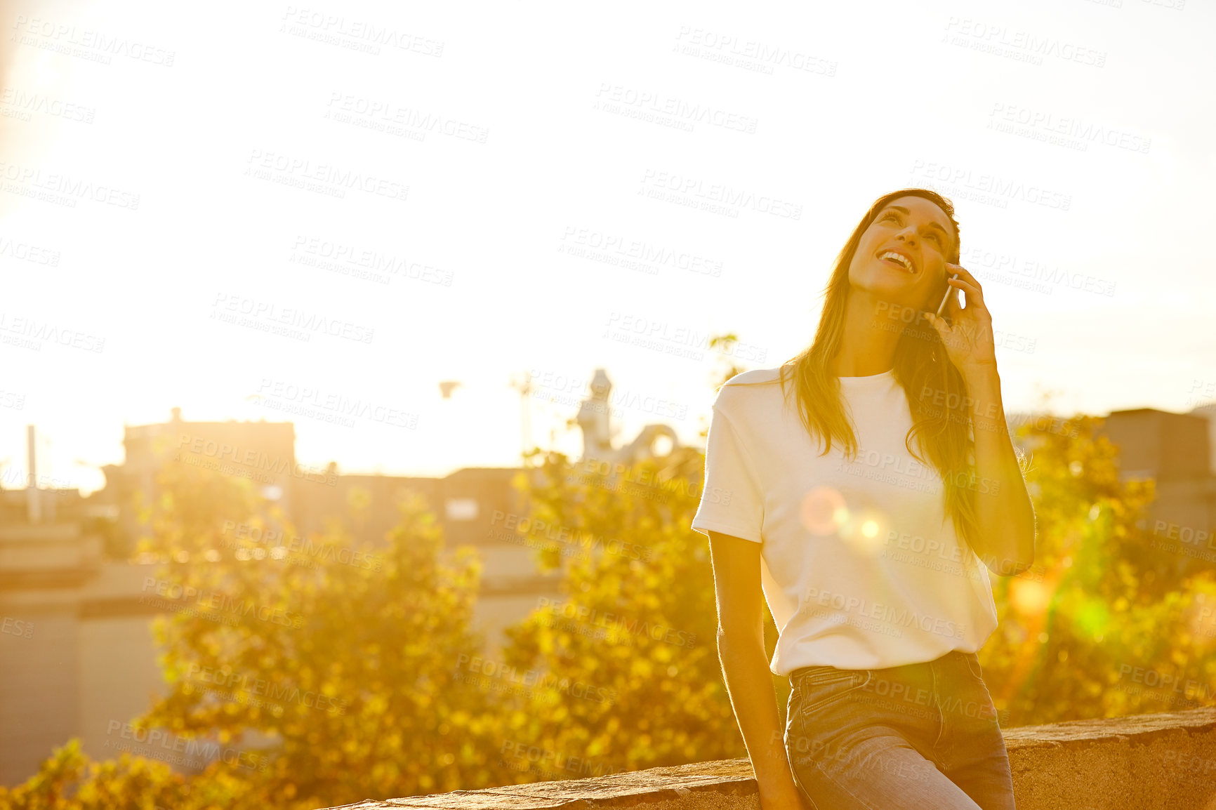 Buy stock photo Shot of a woman talking on her cellphone while standing on a rooftop