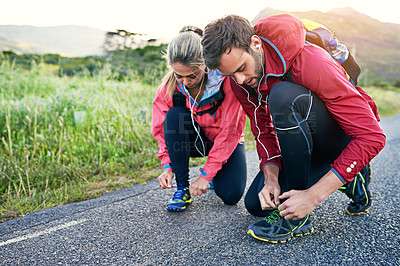 Buy stock photo Full length shot of a young couple tying their laces before a morning run