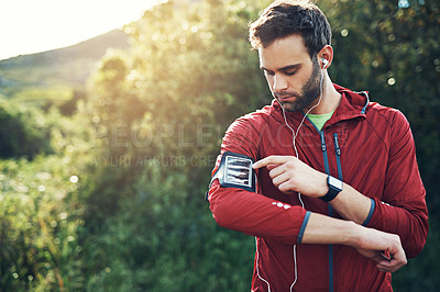 Buy stock photo Cropped shot of a handsome young male athlete preparing his playlist while out for a morning run