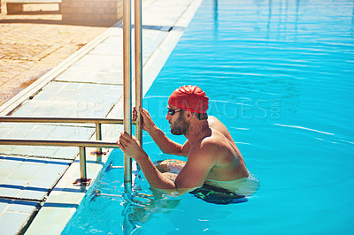 Buy stock photo Cropped shot of a handsome young male swimmer using the ladder to climb out of the swimming pool