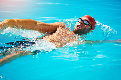 Buy stock photo Shot of a handsome young male swimmer doing backstroke in a swimming pool