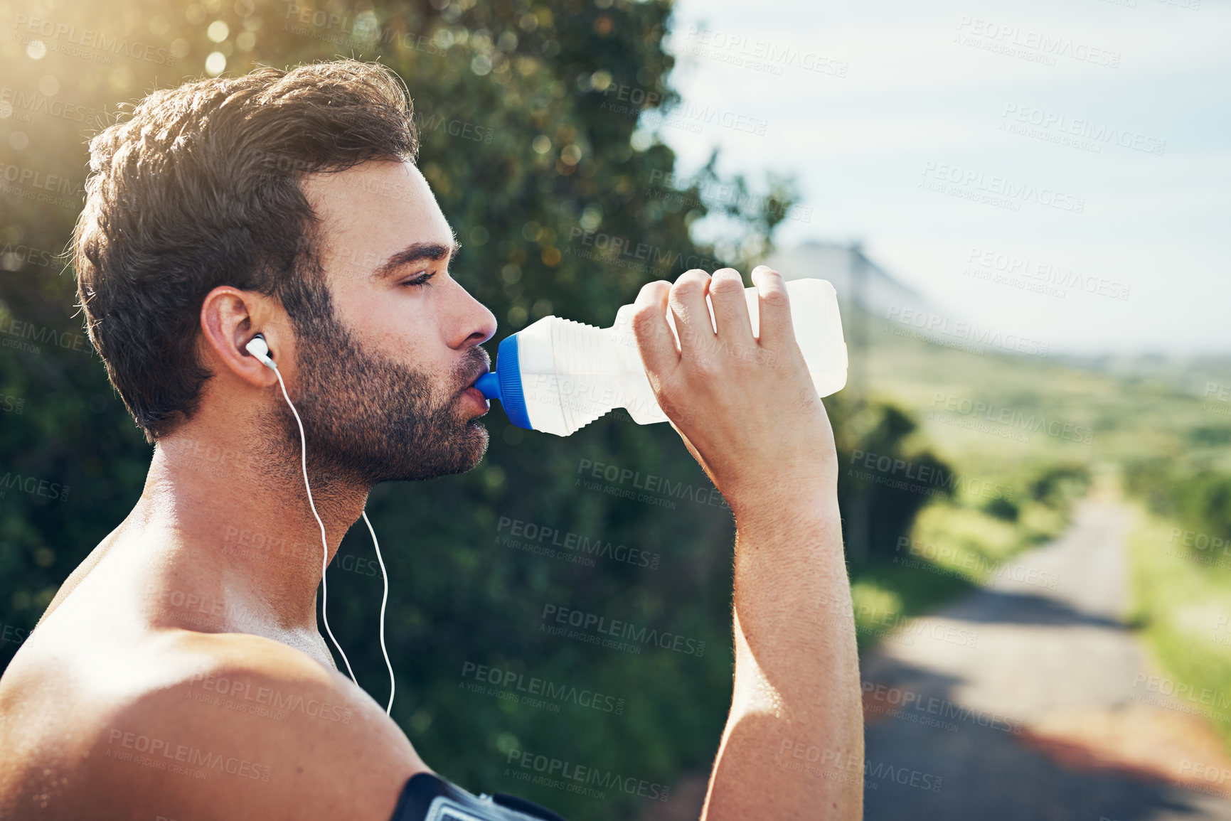 Buy stock photo Cropped shot of a handsome young male athlete drinking water while out for his morning run