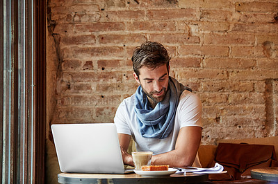 Buy stock photo Shot of a young man working on his laptop while sitting in a cafe
