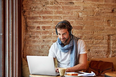 Buy stock photo Shot of a young man working on his laptop while sitting in a cafe