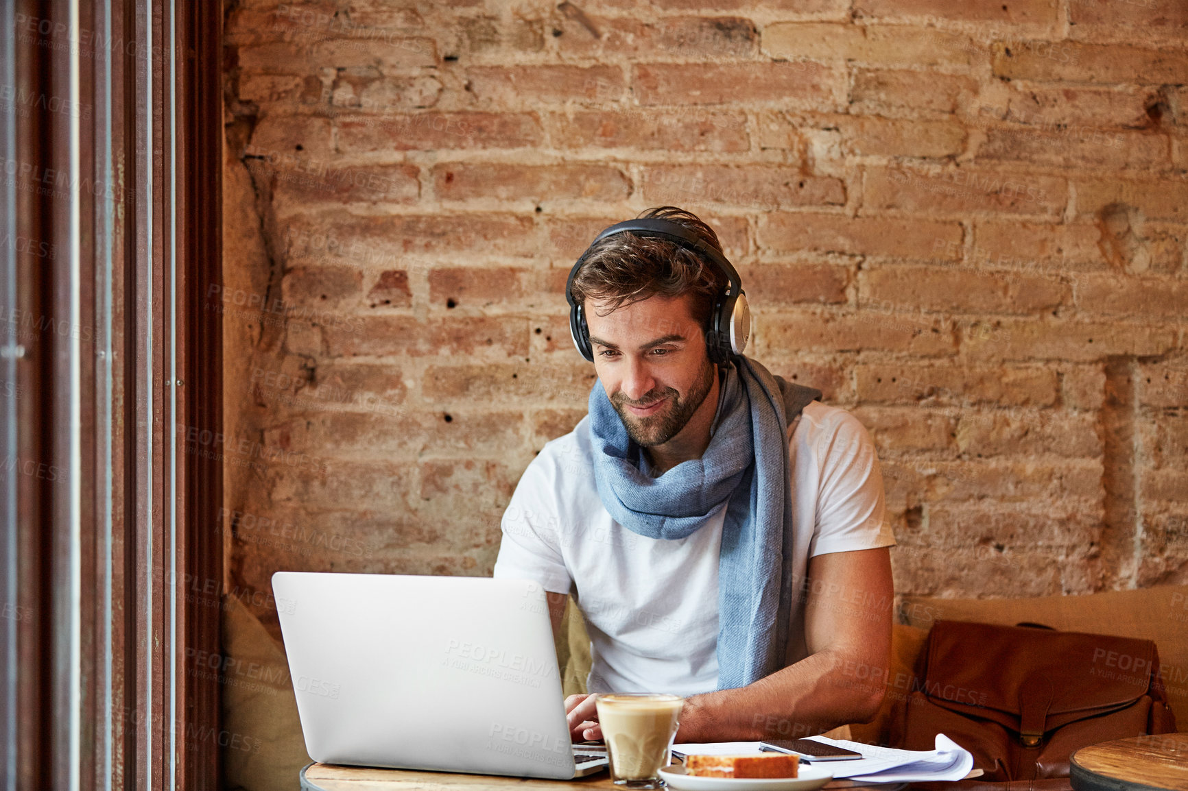 Buy stock photo Shot of a young man working on his laptop while sitting in a cafe