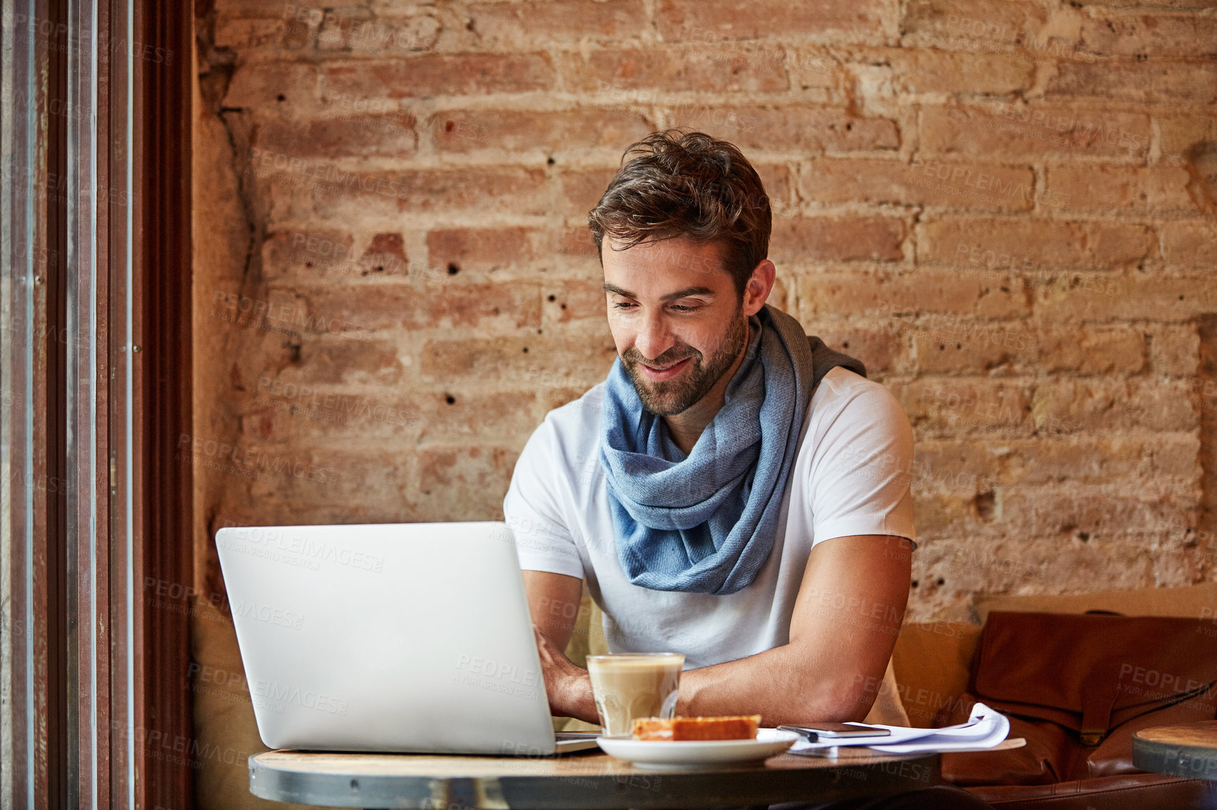 Buy stock photo Shot of a young man working on his laptop while sitting in a cafe