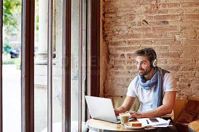 Buy stock photo Shot of a young man working on his laptop while sitting in a cafe